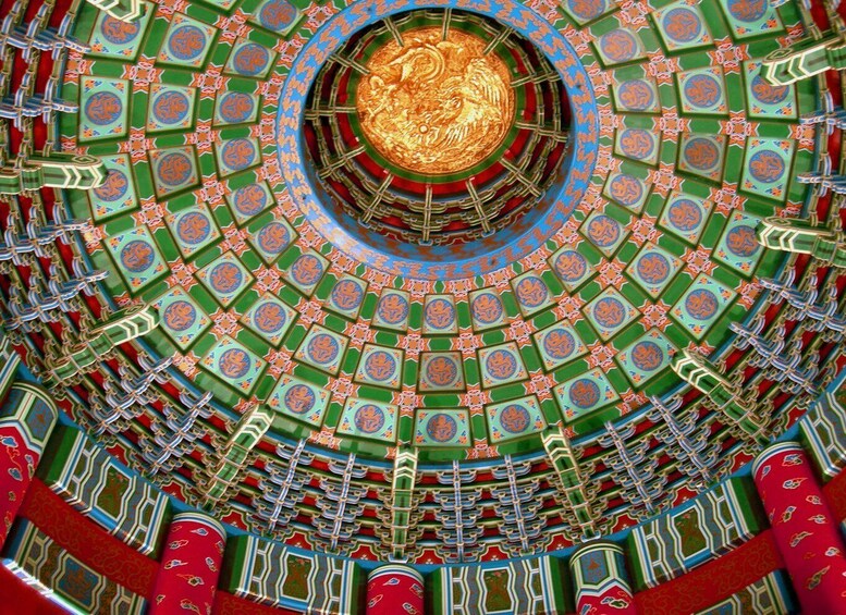A detailed circular ceiling with intricate patterns and a central golden emblem. 1