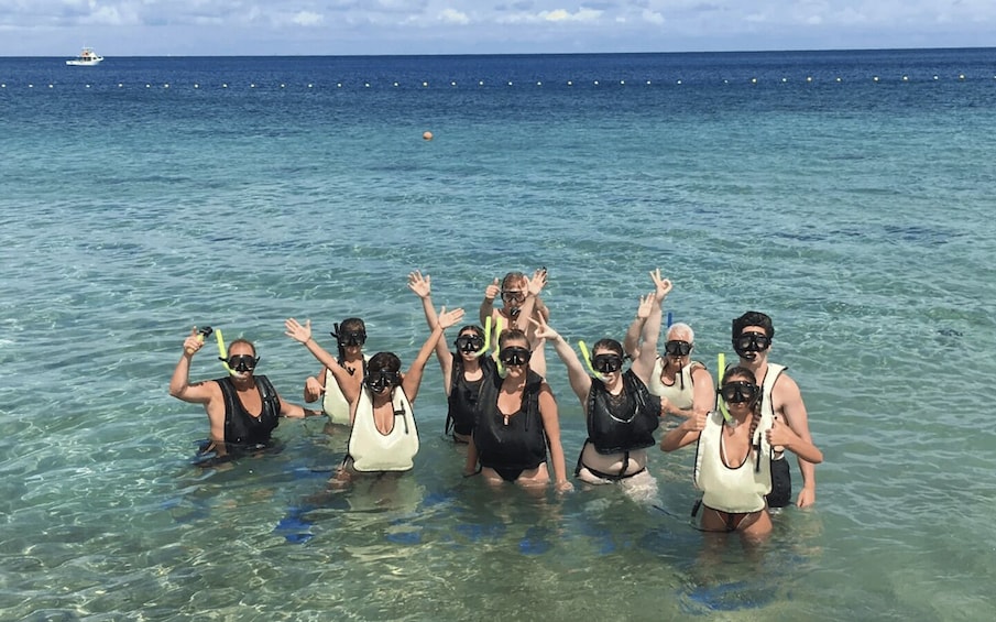 A group of people snorkeling in clear blue water with a boat in the background. 4
