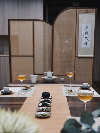 A traditional tea ceremony setup with a tea set, cups, and a tea pot on a wooden table. 1