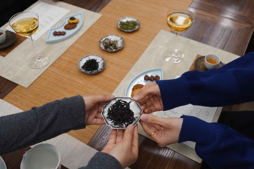 A group of people sharing tea and snacks around a wooden table. 4
