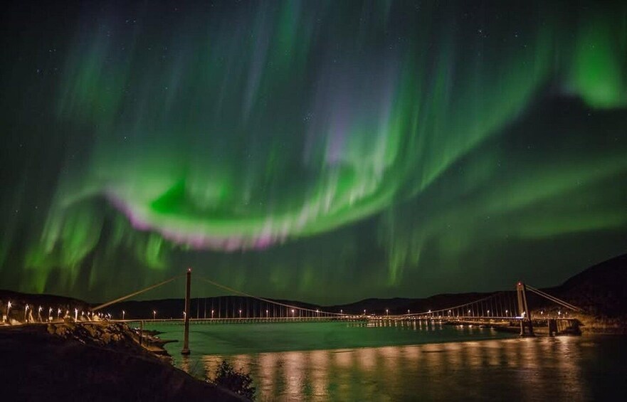 The Northern Lights over a bridge and water at night. 1