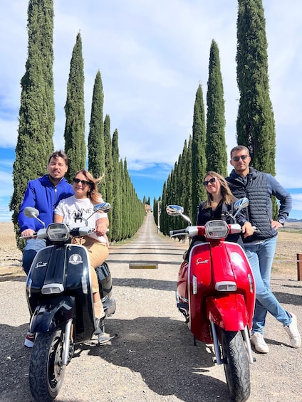 Four people on scooters in a row, lined up with tall cypress trees in the background. 1