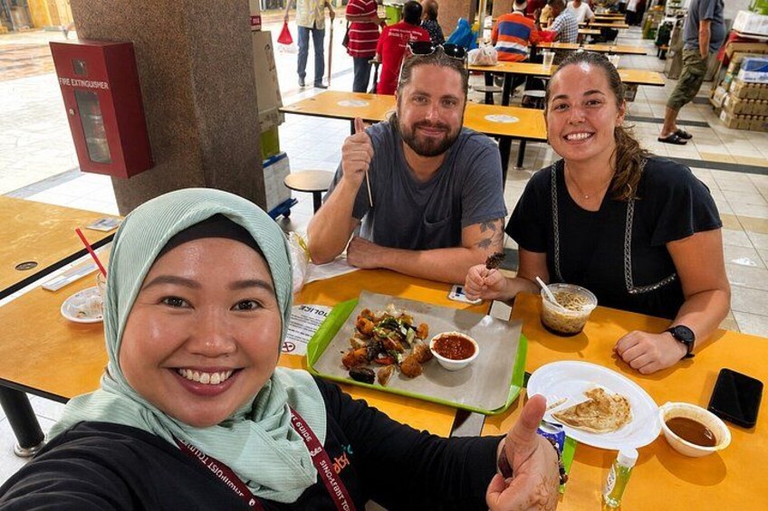 Three people dining at an outdoor restaurant with food and drinks on the table. 3