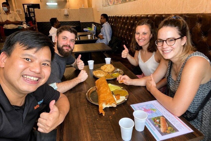 A group of people sitting at a table in a restaurant, giving thumbs up. 2