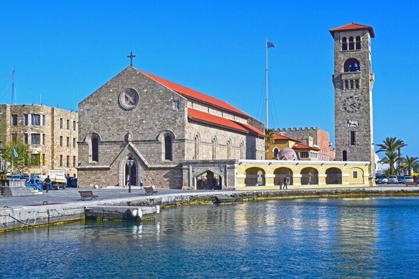 A historic church with a clock tower, a waterfront, and a clear blue sky. 5