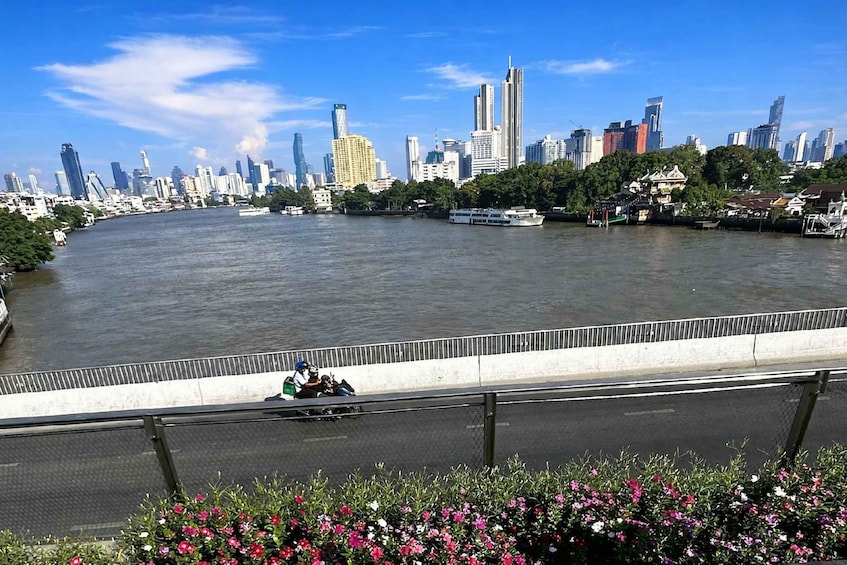 A river with a city skyline in the background, a bridge with a railing, and a boat on the water. 2