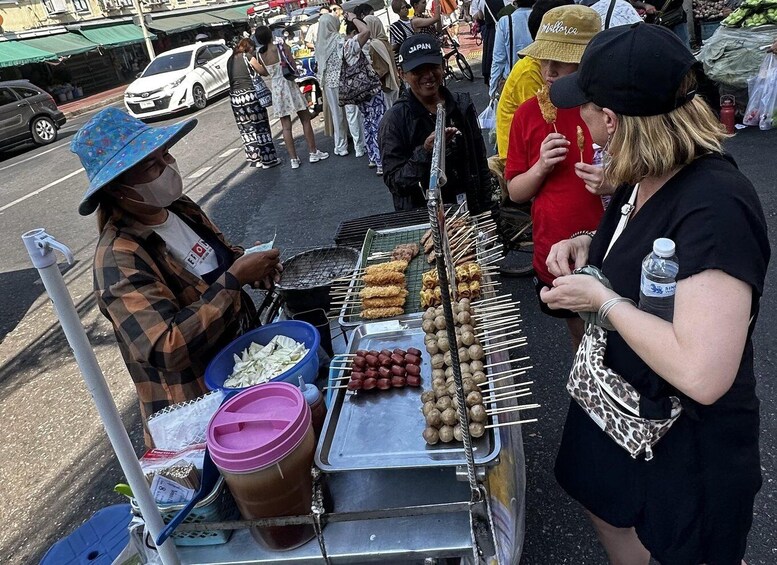 A street food vendor with skewers of food, a water bottle, and a blue container. 3