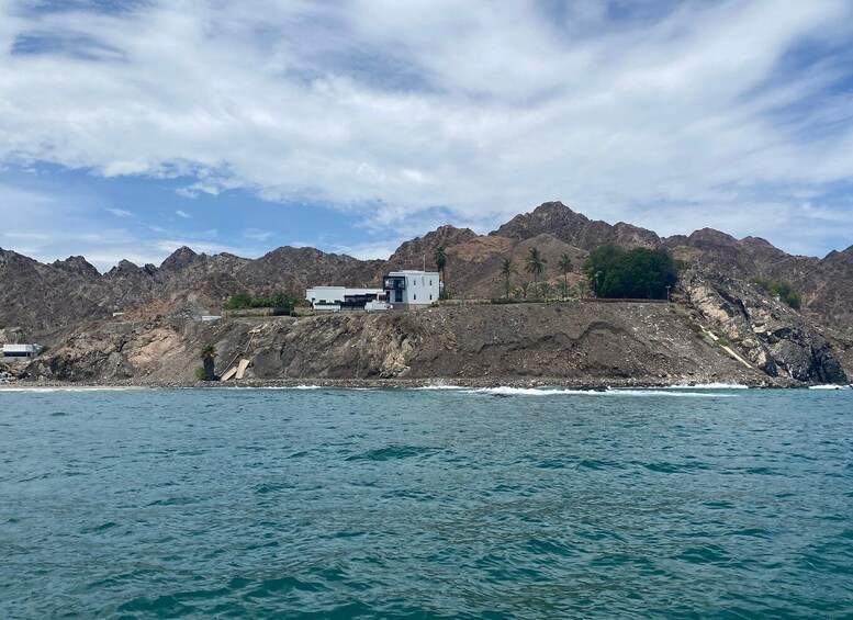A coastal landscape with rocky cliffs, a modern building, and a clear sky. 3