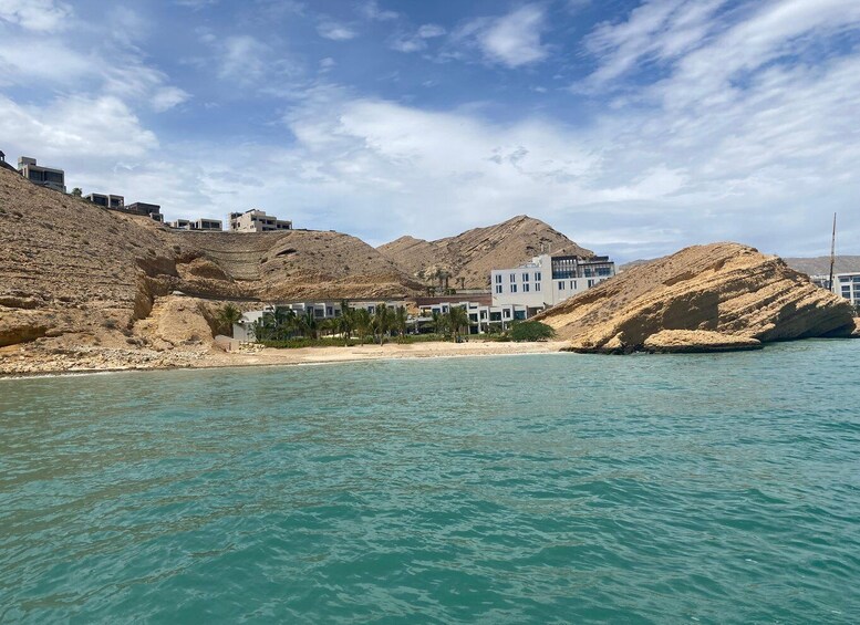 A coastal landscape with buildings, a beach, and a mountain. 5