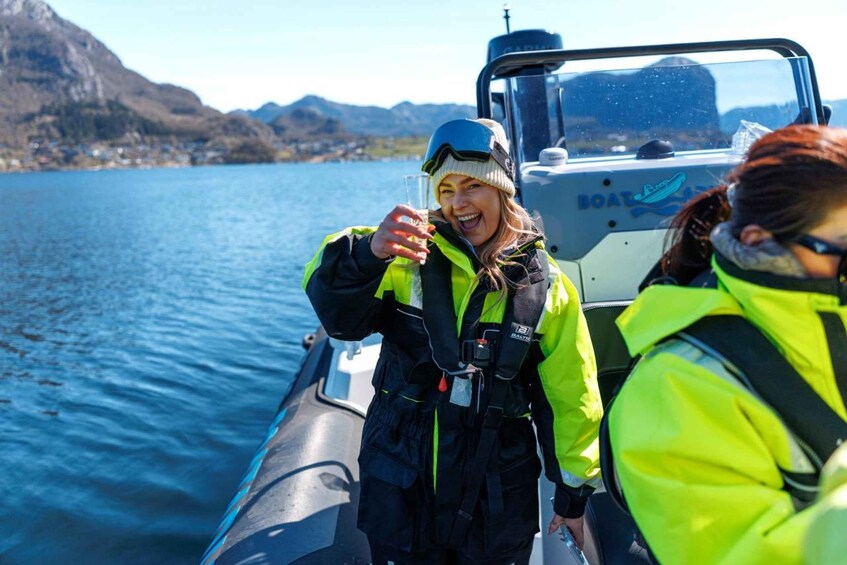 A person in a yellow life jacket on a boat, with a mountainous landscape in the background. 4