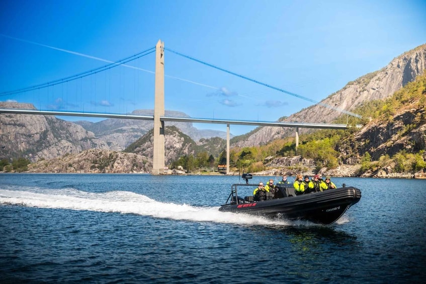 A boat with people wearing life jackets on a lake with a bridge in the background. 3