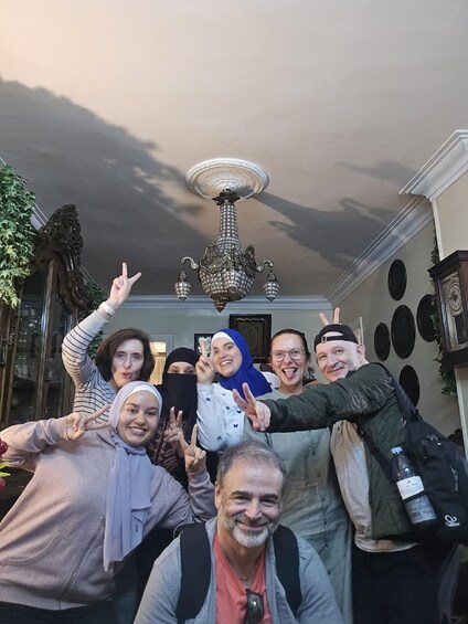 A group of people posing in a hallway with a chandelier and decorative wall elements. 3
