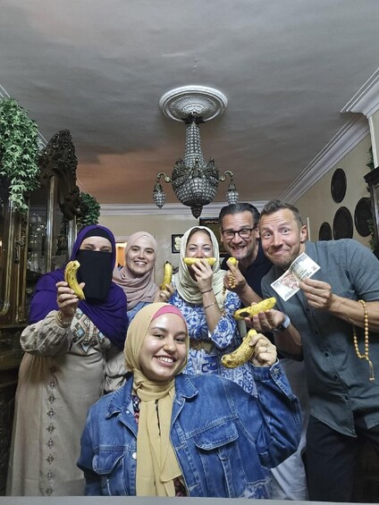 A group of people holding bananas and currency notes in a room with ornate furniture and a chandelier. 4