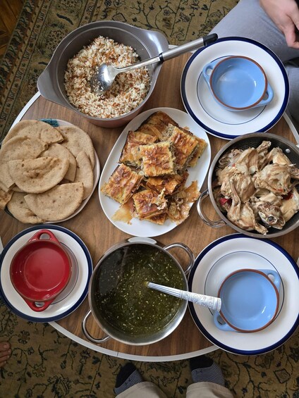 A table with various dishes including rice, flatbread, chicken, and a green sauce. 2