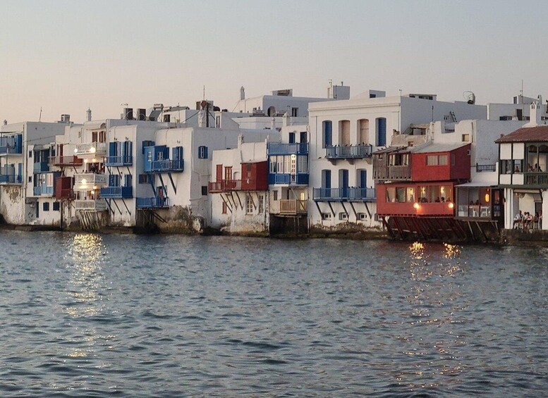 A waterfront with colorful buildings, some with balconies, and reflections on the water. 1