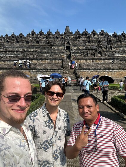 A group of people standing in front of a large, ancient stone structure with multiple levels and intricate carvings. 3