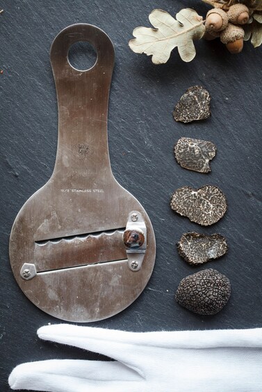 A metal tool with a hole at the top and a serrated edge, accompanied by a white fabric and various textured objects. 1