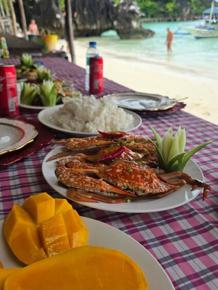 A meal with crab, rice, and mango on a table by a beach. 3