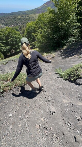 A person hiking on a rocky trail with a mountainous landscape in the background. 1