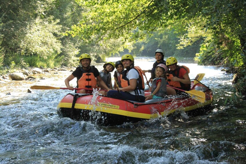 A group of people in a raft on a river surrounded by greenery. 3