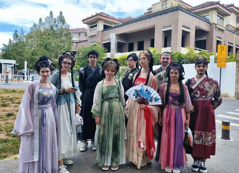 A group of people in traditional costumes standing in front of a building with a parking sign. 3
