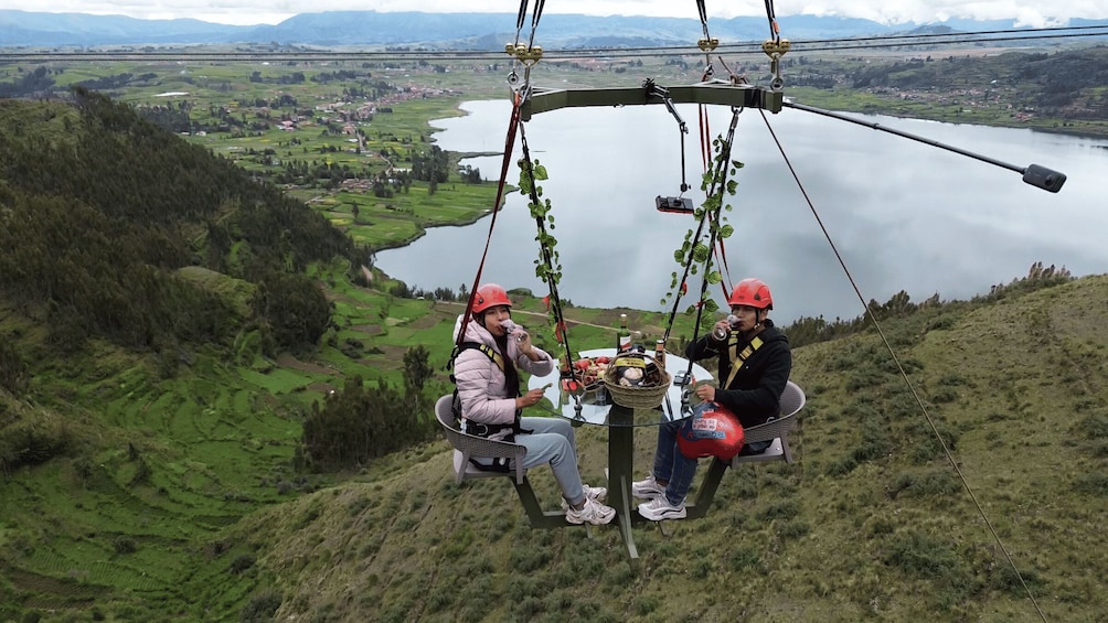 Two people on a cable car with a scenic view of a lake and mountains. 3