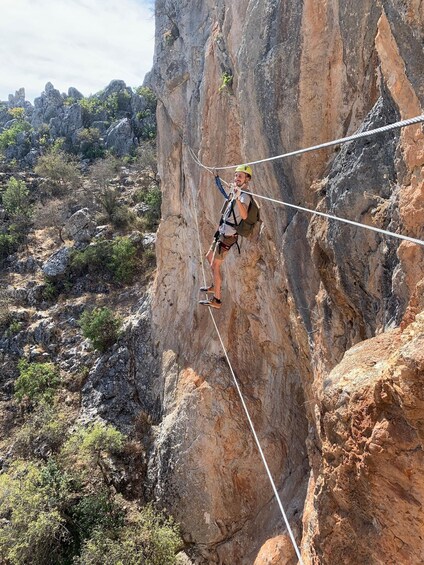 A person rock climbing a steep cliff with ropes. 3