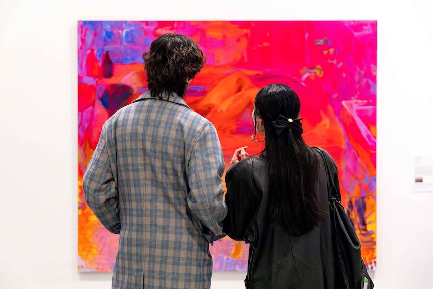 Two people viewing a colorful abstract painting in an art gallery. 3
