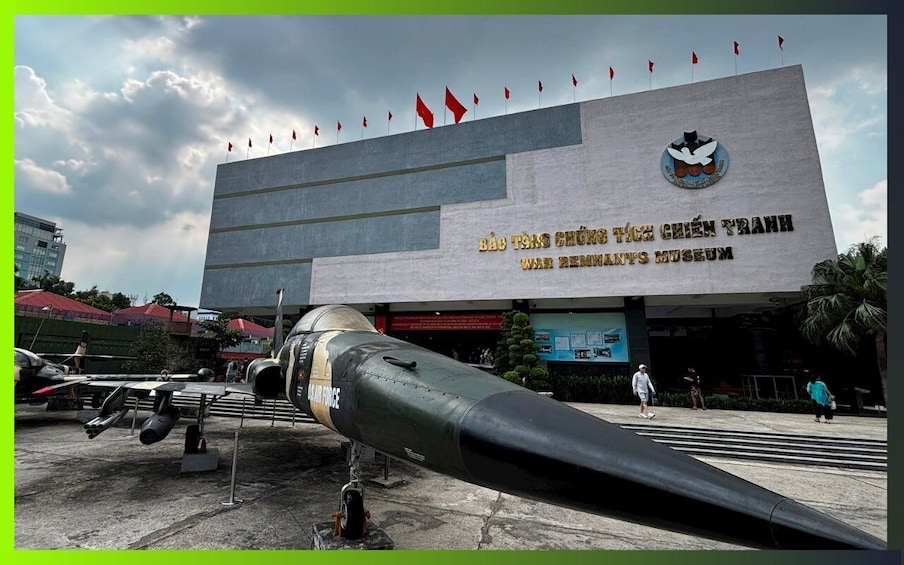 A military aircraft on display in front of a building with flags and a logo. 3