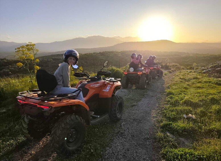 A group of people riding ATVs on a dirt path with a sunset in the background. 1