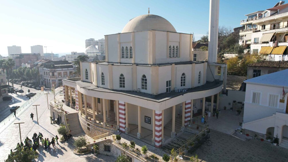 A multi-story building with a dome, surrounded by urban structures and pedestrians. 5