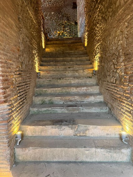 A stone staircase with brick walls, leading to an upper level. 5
