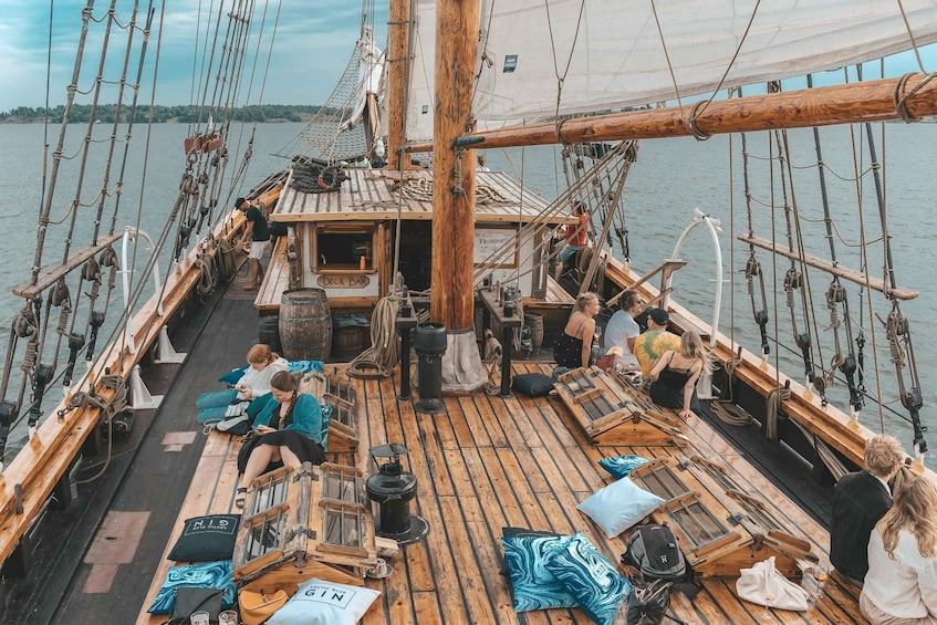 A wooden deck with people sitting and standing, a sign reading 'DECK BAR,' and a view of the water. 4