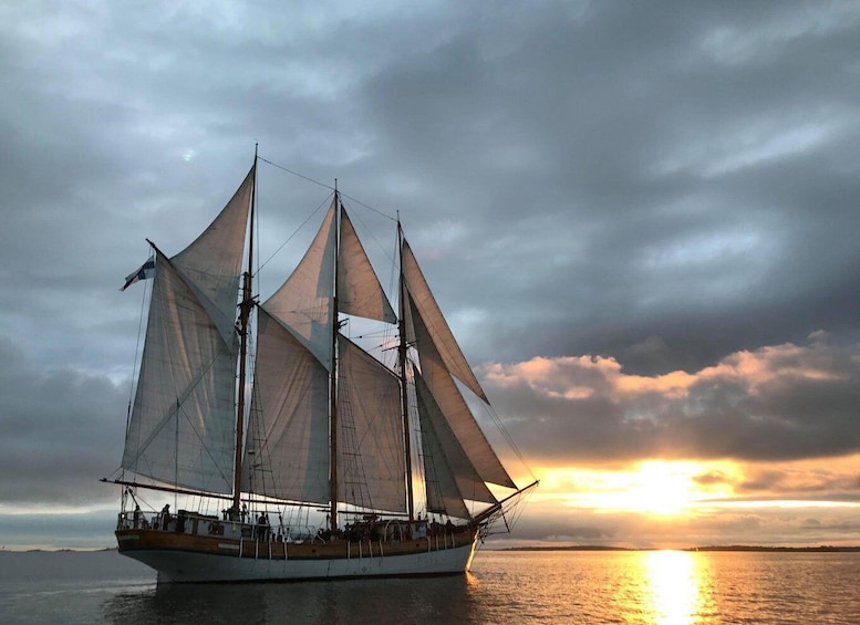 A sailing ship with multiple sails, a crew, and a sunset in the background. 3