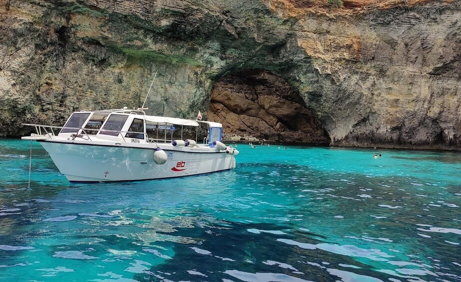 A boat anchored near a rocky cliff with clear turquoise water. 5