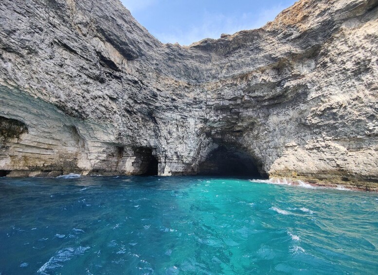 A natural rock formation with a clear blue pool at its base. 4