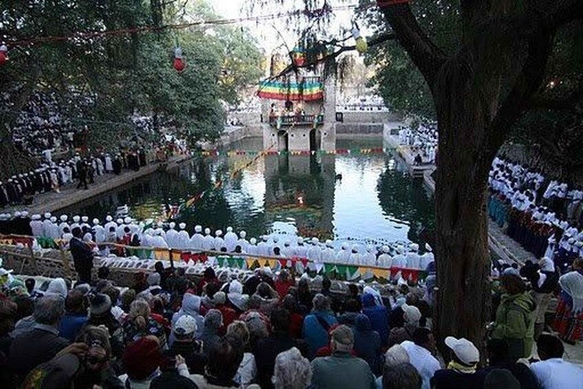 A crowd gathered around a river, with a bridge and a colorful structure in the background. 5