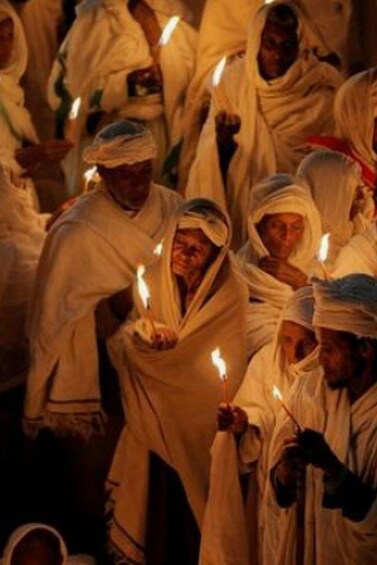 A group of people in white robes holding candles. 5