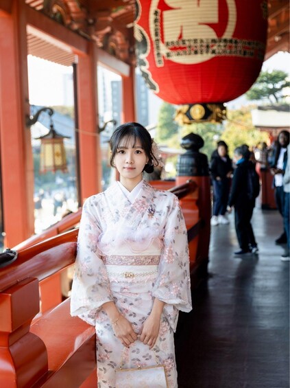 A person in traditional attire standing in front of a red lantern. 2