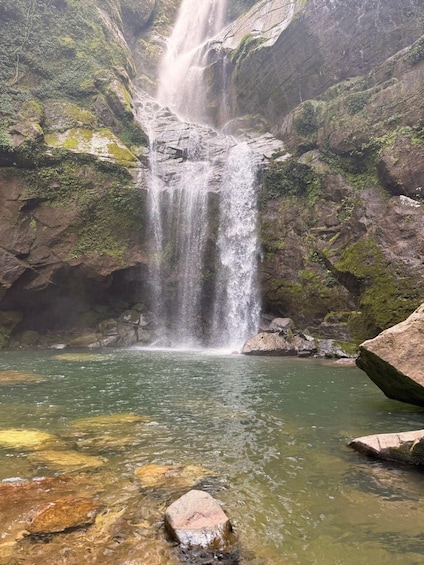 A waterfall cascading into a clear pool surrounded by moss-covered rocks. 2