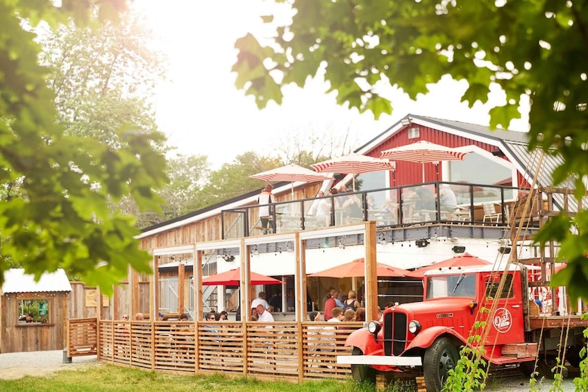 A red truck parked in front of a wooden building with red and white striped umbrellas. 3