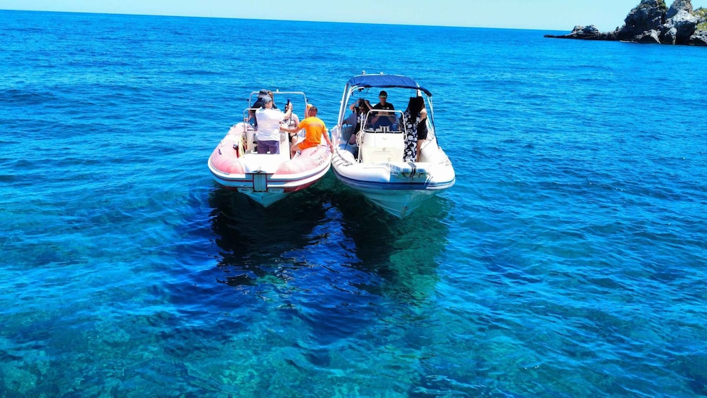 Two inflatable boats on clear blue water with rocky outcrops in the background. 3