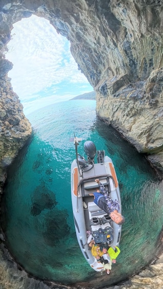 A boat anchored in a natural rock arch formation with clear turquoise water. 5