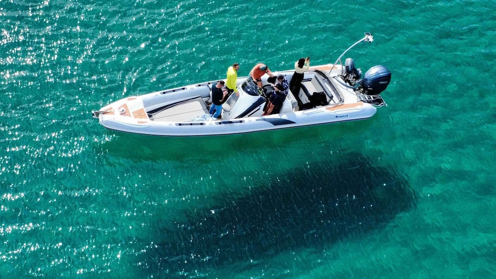 A small motorboat with several people on board, floating on clear turquoise water. 1
