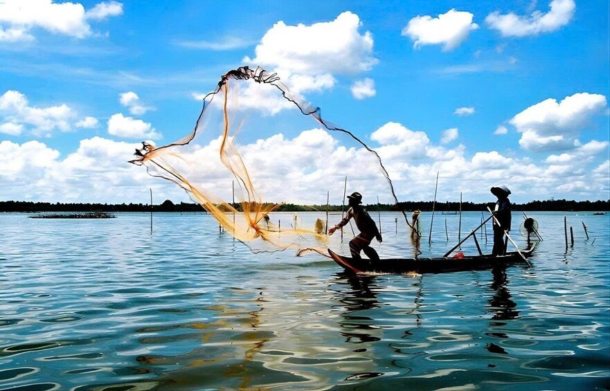 Two people on a boat with a fishing net in the water. 3