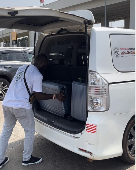 A white van with its back door open, a person loading luggage into the cargo area, and a sign on the van indicating 'Expedition-Go Tours Ltd.' 4