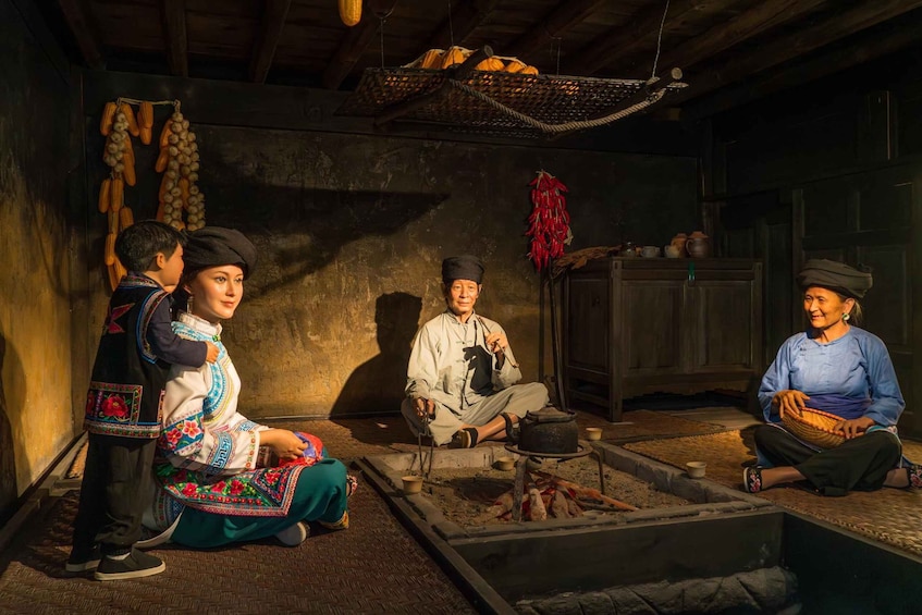 A traditional setting with people in cultural attire, a fire pit, and rustic wooden walls. 2