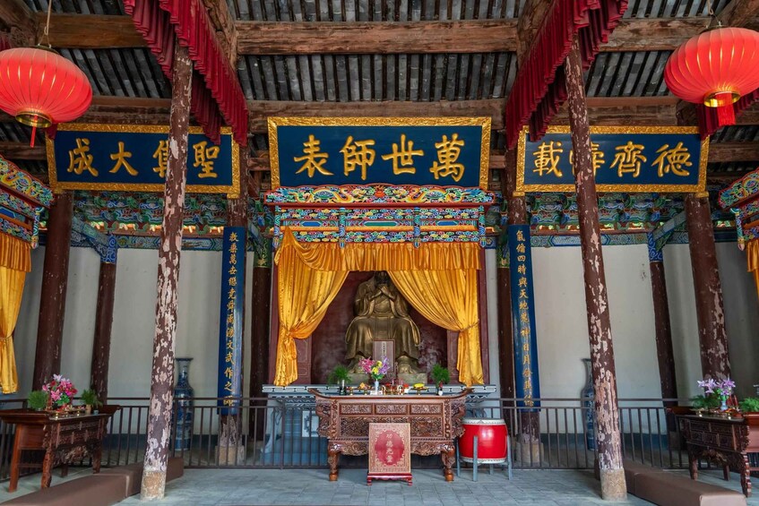 A traditional Chinese temple interior with a large golden statue, ornate decorations, and red lanterns. 3