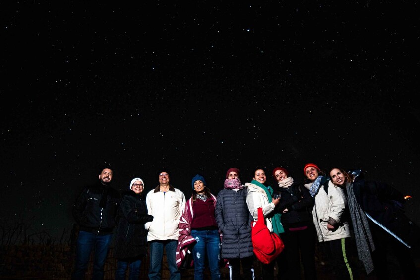 A group of people standing outdoors at night under a starry sky. 5