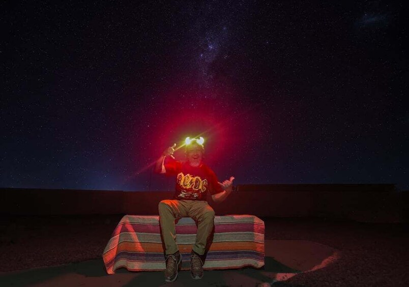 A person sitting on a striped bench under a starry sky. 4